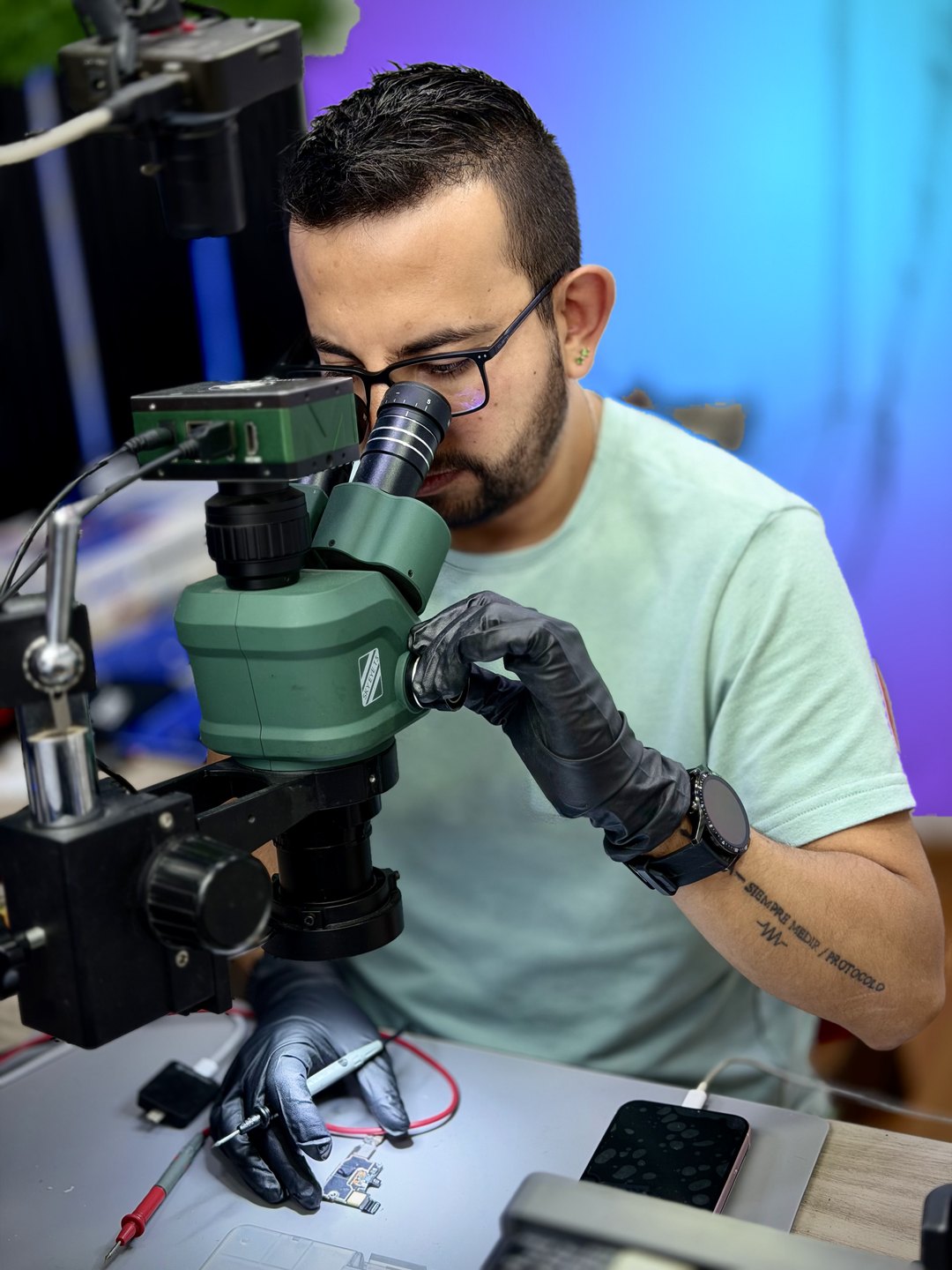 Henry reparando una placa de iPhone con microscopio en el taller de HENRYIFIX